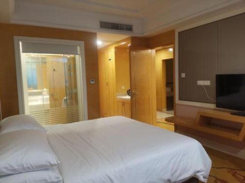 a bedroom with a bed and a flat screen tv at Vienna Hotel Guangdong Huiyang Qiuchang Yingbin Road in Huizhou