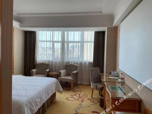 a hotel room with a bed and chairs and a window at Vienna Hotel Guangdong Huiyang Qiuchang Yingbin Road in Huizhou