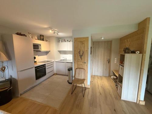 - une cuisine avec des placards blancs et une chaise dans la chambre dans l'établissement Nid douillet à la montagne, à Valmorel