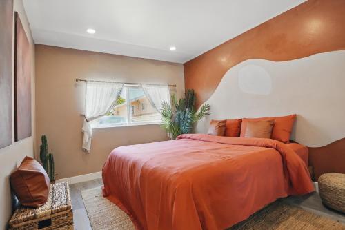 a bedroom with a large bed with an orange bedspread at La Tierra House 15 Min to Beach Movie Lounge in Hawthorne