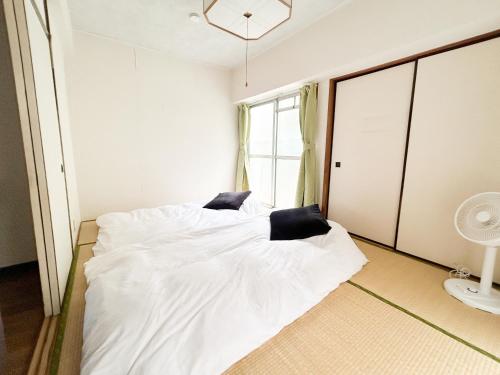 a bedroom with a white bed with two black pillows at 駅から徒歩5分池袋まで電車で5分の好立地 in Tokyo