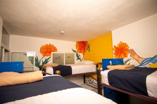a room with three beds with flowers on the wall at Hostal Talavera in Puebla