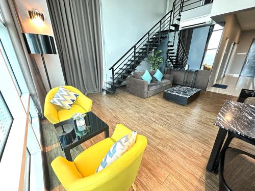 a living room with yellow chairs and a staircase at Amazing Seaview Duplex George Town Maritime Suites 20 in George Town