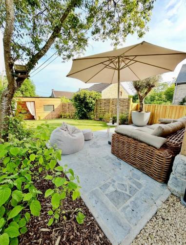 a patio with a couch and an umbrella at Au ptit Gaston in Durbuy