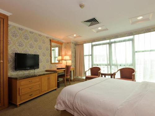 a hotel room with a bed and a desk and a television at New Pearl River Hotel in Guangzhou