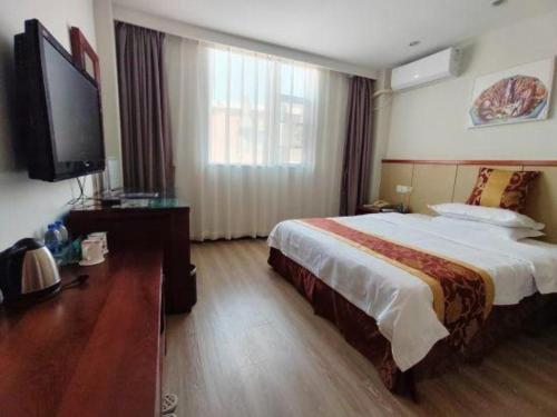 a hotel room with a bed and a flat screen tv at GreenTree Inn Shenzhen Kengzi Town Express Hotel in Kengzi