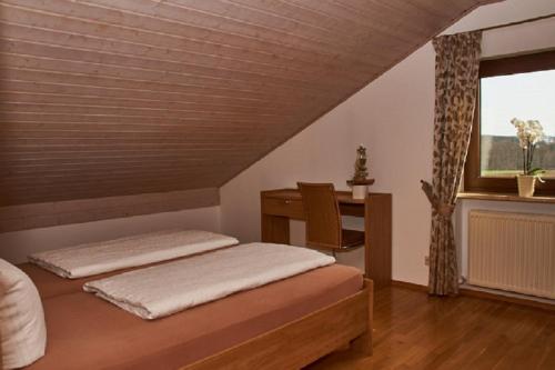 1 dormitorio con 2 camas, escritorio y ventana en Ferienwohnung Achhammer, en Riedenburg