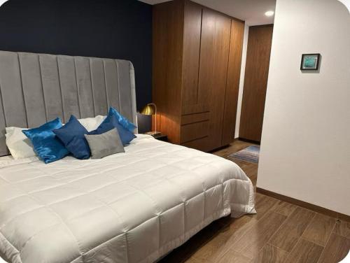 a bedroom with a large white bed with blue pillows at Punto cero in Morelia