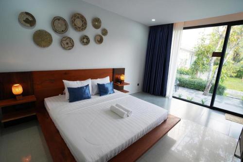Un dormitorio con una gran cama blanca con almohadas azules. en Alice Villa Hotel, en Takeo