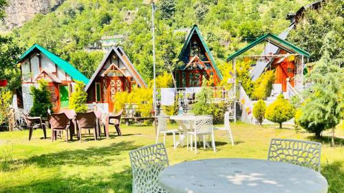 un tavolo e delle sedie davanti a un gruppo di case di A Shape River Side Cabin a Jāmb