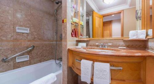 a bathroom with a tub and a sink and a mirror at Regency Hotel in Shantou