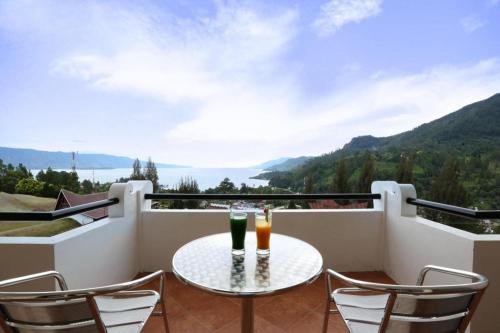 a balcony with a table and two drinks on it at Hotel Niagara Parapat in Parapat