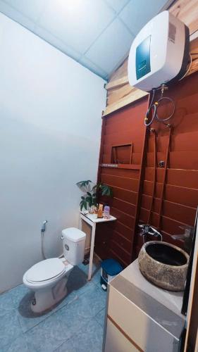a bathroom with a toilet and a tv on the wall at The Fullhouse in Da Lat