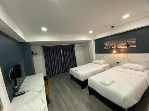 ein Hotelzimmer mit zwei Betten und einem Fernseher in der Unterkunft Prinn Hotel in Ban Thai Wat Khot