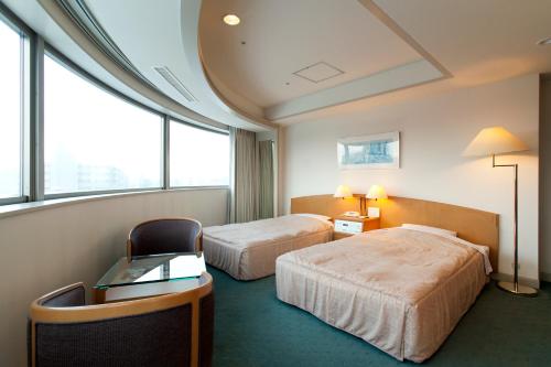 a hotel room with two beds and a desk and windows at Jasmac Plaza Hotel in Sapporo