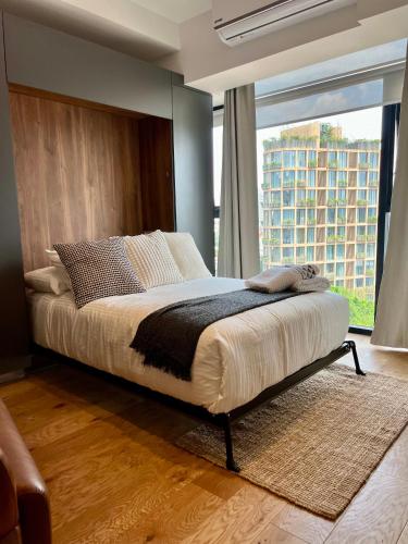 a bedroom with a large bed with a large window at Hermoso Loft en la Roma Norte in Mexico City