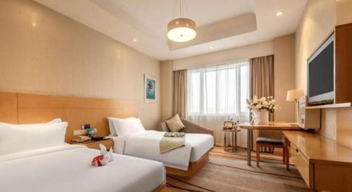 a hotel room with two beds and a television at Huachen Kenzo Hotel Hangzhou in Hangzhou