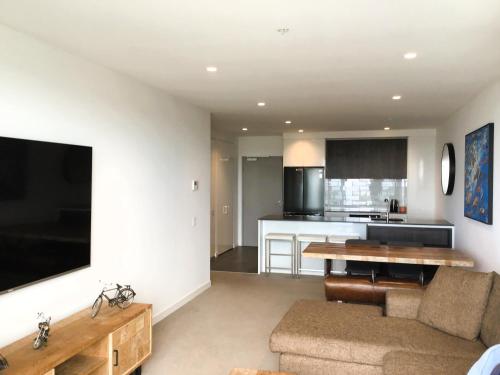 a living room with a couch and a table and a kitchen at MIRAMAR APARTMENTS 2 Bedroom Apartment with Bay Views on the Geelong Waterfront - 0504 in Geelong
