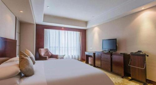 a hotel room with a bed and a flat screen tv at Hohhot Hai Liang Plaza Hotel in Hohhot