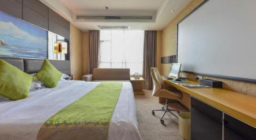 a hotel room with a bed and a desk with a computer at GreenTree Alliance Shenzhen Shekou Sea World Hotel in Shenzhen