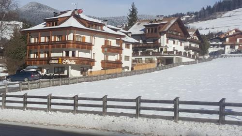 a large building in the snow next to a fence at Residence Garni Stella in San Vigilio Di Marebbe