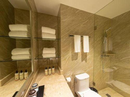a bathroom with a shower and a toilet and towels at Landmark Hotel in Zhuhai