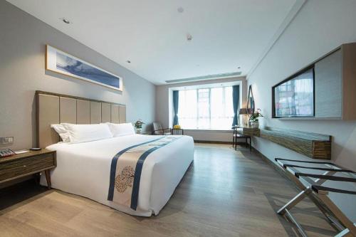 a large bedroom with a large white bed and windows at Landmark Hotel in Zhuhai