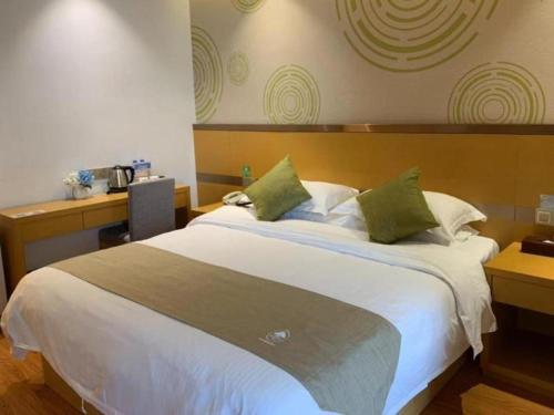 a bedroom with a large white bed with green pillows at GreenTree Inn Fuzhou Gulou District West Xierhuan Road Zuohai Park in Fuzhou