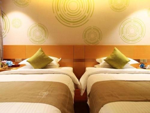 a hotel room with two beds with green pillows at GreenTree Inn Fuzhou Gulou District West Xierhuan Road Zuohai Park in Fuzhou