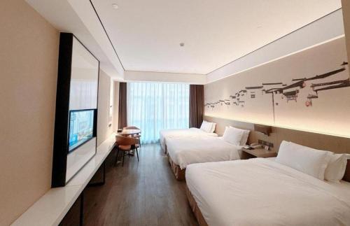 a hotel room with two beds and a flat screen tv at GRACE Select Hotel (Kunshan Huaqiao International Convention Center) in Suzhou