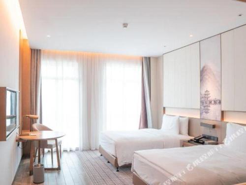 a hotel room with two beds and a desk and a table at Wanda JIN Baise in Baise