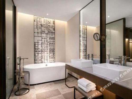 a bathroom with two sinks and a bath tub at Wanda JIN Baise in Baise