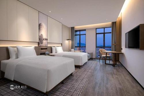 a hotel room with two beds and a flat screen tv at Wanda JIN Baise in Baise