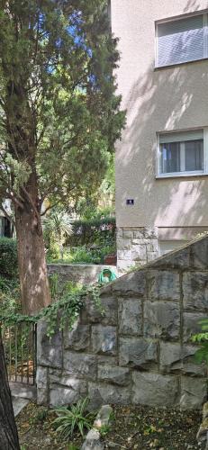 a stone wall next to a tree and a building at LaMar Bačvice in Split