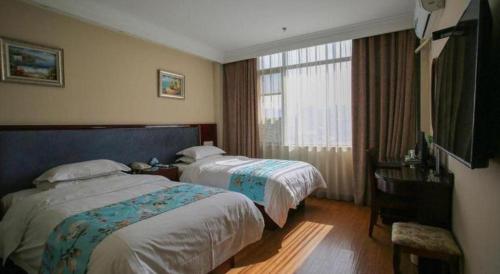 ein Hotelzimmer mit zwei Betten und einem Fenster in der Unterkunft GreenTree Inn Jiangsu Wuxi Xishan DongTing Erquan East Road XinGuang Newly Estate Express Hotel in Wuxi