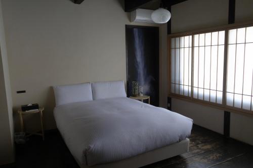 a bedroom with a white bed and a window at Machiya-Hotel Kyoto-ba 町屋ホテル 京都宿 in Kyoto