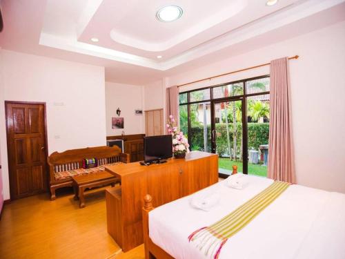 une chambre avec un lit et un bureau avec un ordinateur dans l'établissement Rommai Reunngam Resort, à Ban Chang Kham Luang