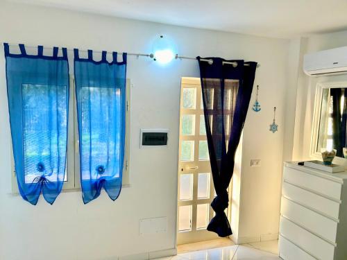 a room with two blue curtains and a door at DEPANDANCE SUL MARE in Sperlonga