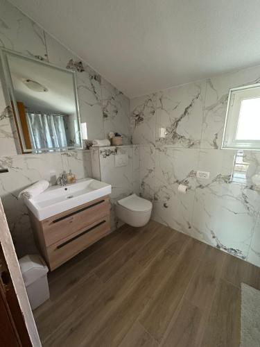 a bathroom with a sink and a toilet and a mirror at Apartmani Krpeta in Pakoštane