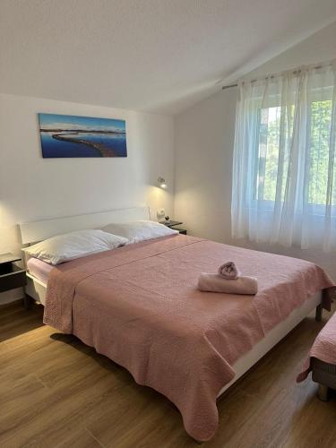 a bedroom with a large bed with a pink blanket at Apartmani Krpeta in Pakoštane