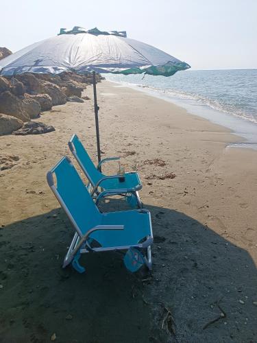 a blue beach chair under an umbrella on the beach at Blue Aura Beach villa Larnaca in Pervolia