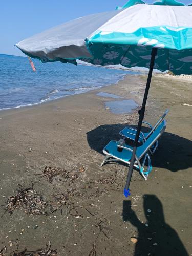 a beach chair and an umbrella on the beach at Blue Aura Beach villa Larnaca in Pervolia
