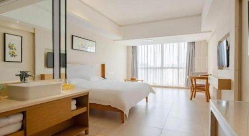a bathroom with a bed and a sink in a room at Da Peng Zhongzhou Hotel in Haikou