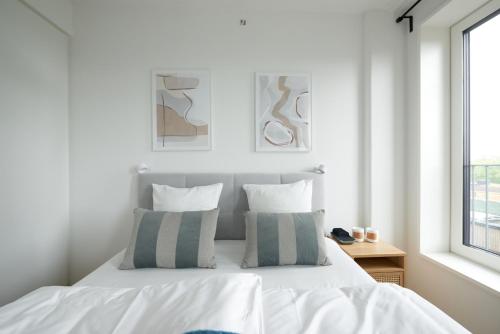 a white bedroom with a white bed with two pillows at Elegant Cozy Modern Free Parking in Copenhagen