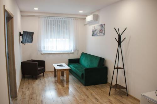 Una sala de estar con un sofá verde y una mesa. en PRZYSTANEK ROSZKÓW -NOCLEGI i RESTAURACJA, en Roszków