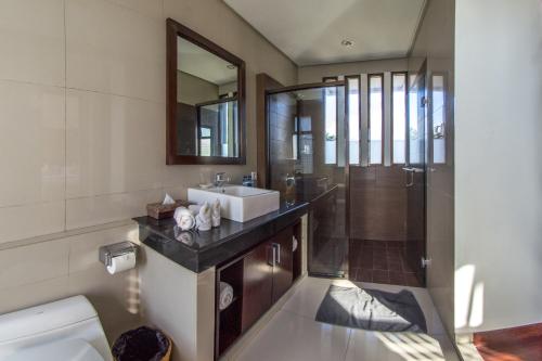 y baño con lavabo, aseo y espejo. en Villa Uma Girasole, en Canggu