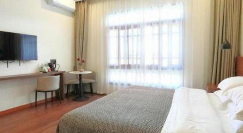 a bedroom with a bed and a desk and a window at Lijiang Liwang Hotel in Lijiang