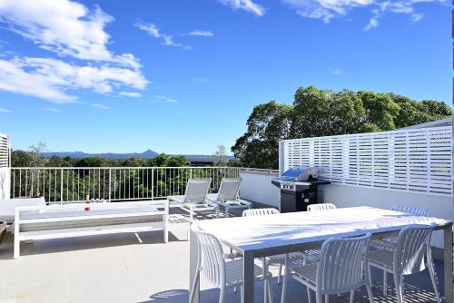 a patio with white chairs and a table and a bench at Casa Katharina – Your Coastal Escape on Noosa Hill in Noosa Heads