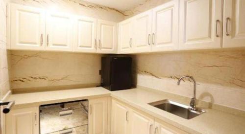 a kitchen with white cabinets and a sink at Weida Hotel Jinhua in Jinhua