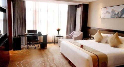 a hotel room with a large bed and a desk at Weida Hotel Jinhua in Jinhua